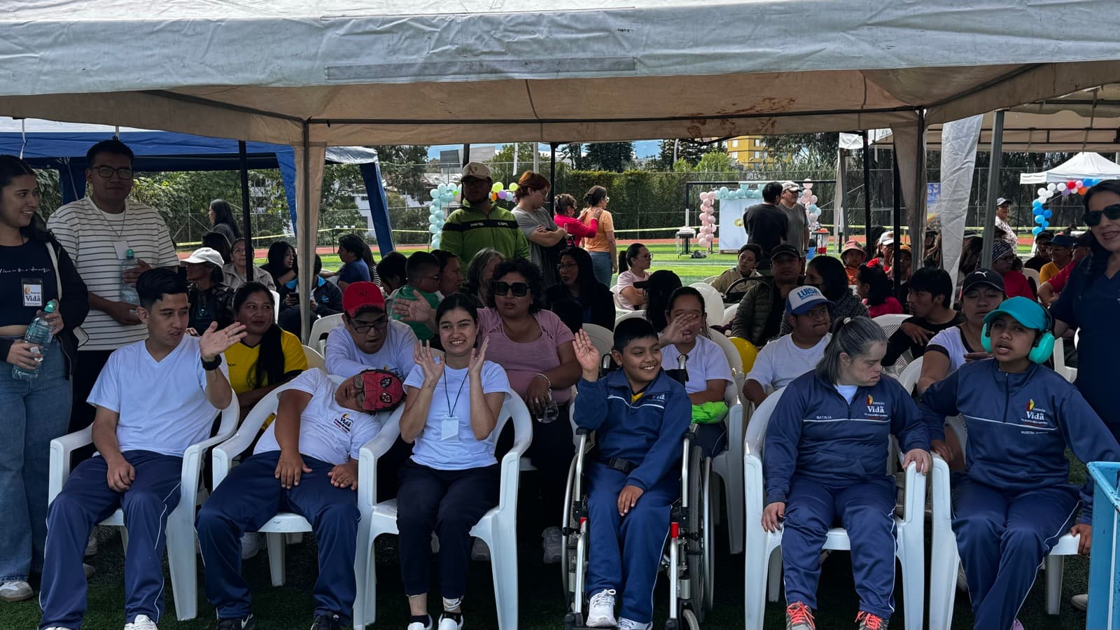 Familias y beneficiarios de HSD reunidos bajo una carpa durante el evento